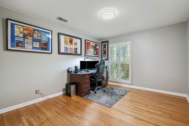 office area with wood finished floors, visible vents, and baseboards