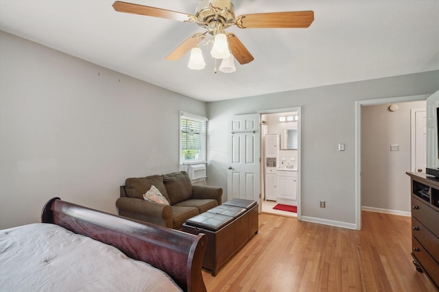 bedroom featuring light wood finished floors, ensuite bath, baseboards, and ceiling fan
