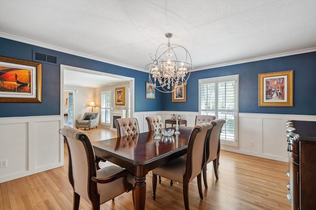 dining room featuring wainscoting, visible vents, and a decorative wall