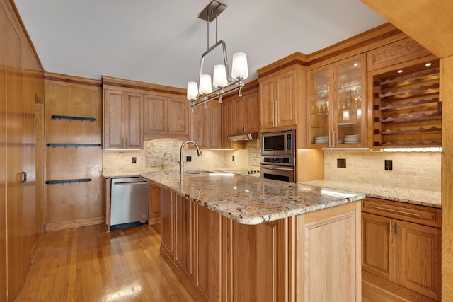 kitchen featuring light stone counters, decorative backsplash, stainless steel appliances, and a sink