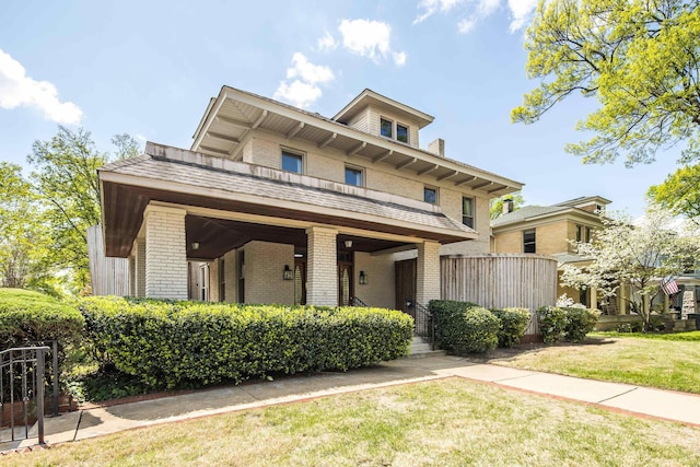 italianate-style house featuring a porch, brick siding, and a front yard