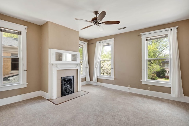 unfurnished living room featuring a wealth of natural light, a fireplace, visible vents, and carpet floors