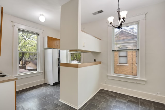 unfurnished dining area featuring an inviting chandelier, visible vents, and baseboards
