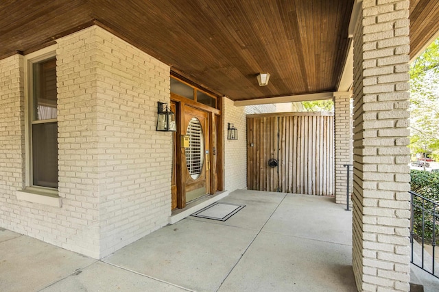 view of exterior entry featuring a porch and brick siding