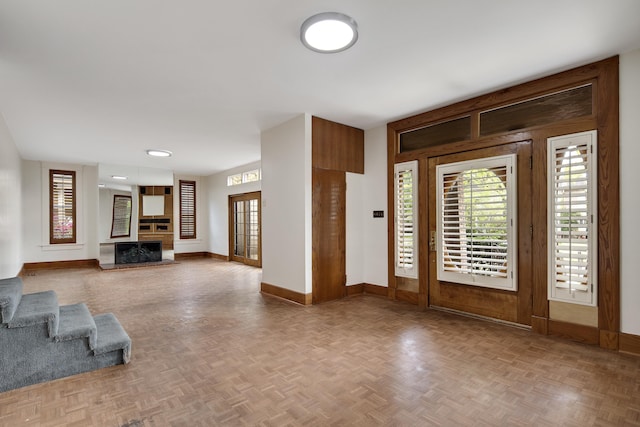 foyer featuring baseboards, french doors, wooden walls, and a fireplace