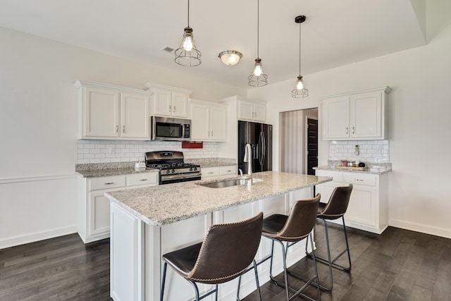 kitchen featuring backsplash, appliances with stainless steel finishes, dark wood-type flooring, and a sink