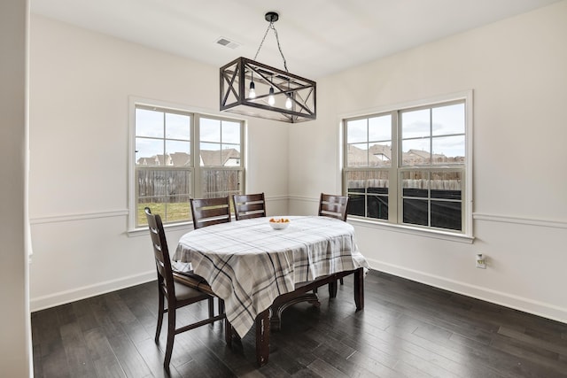 dining space with dark wood-type flooring, visible vents, baseboards, and an inviting chandelier
