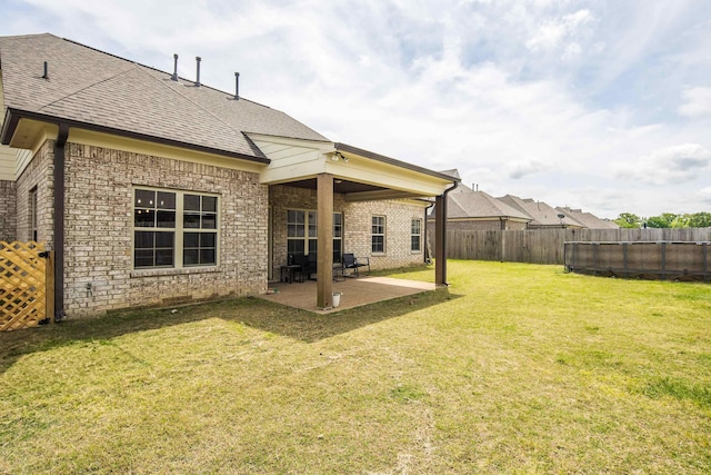 back of property featuring a fenced backyard, a yard, roof with shingles, a patio area, and brick siding