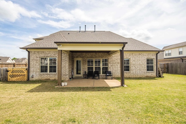 rear view of property with a fenced backyard, brick siding, a shingled roof, a yard, and a patio