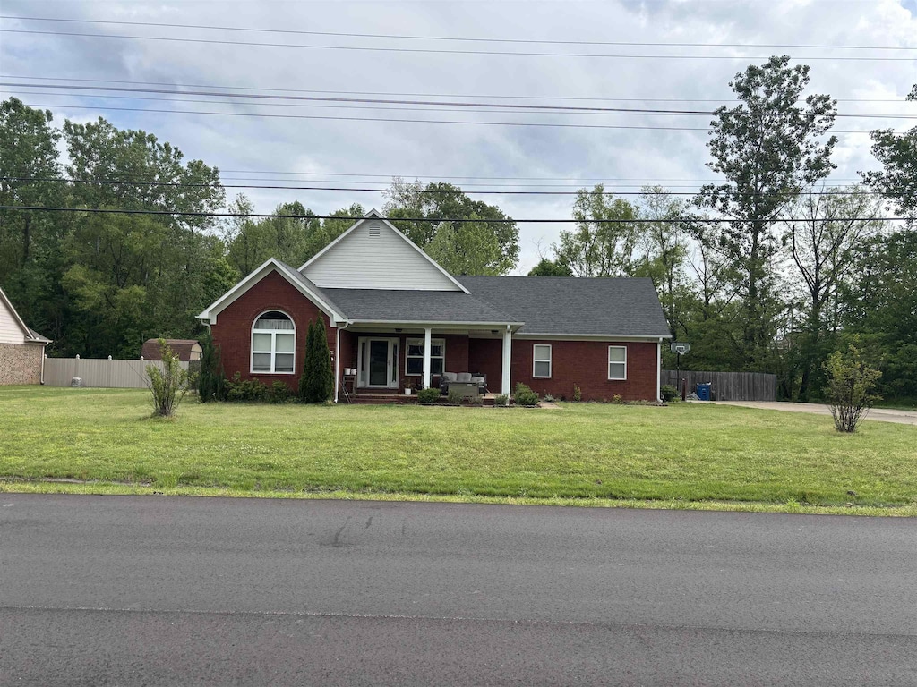 view of front of property featuring brick siding, a front yard, covered porch, and fence