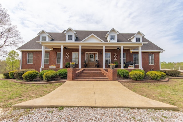 new england style home with ceiling fan, covered porch, and brick siding