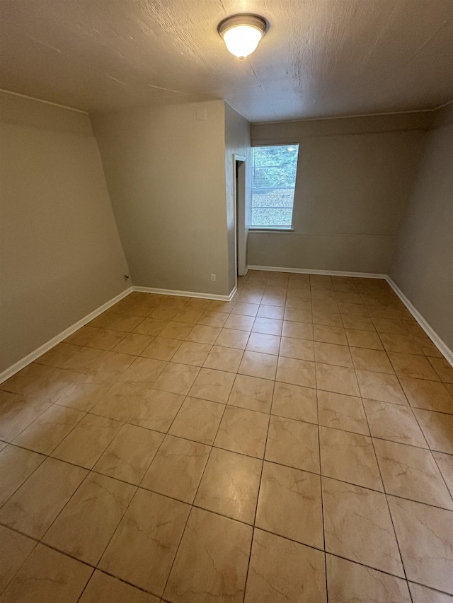 bonus room with baseboards and light tile patterned floors