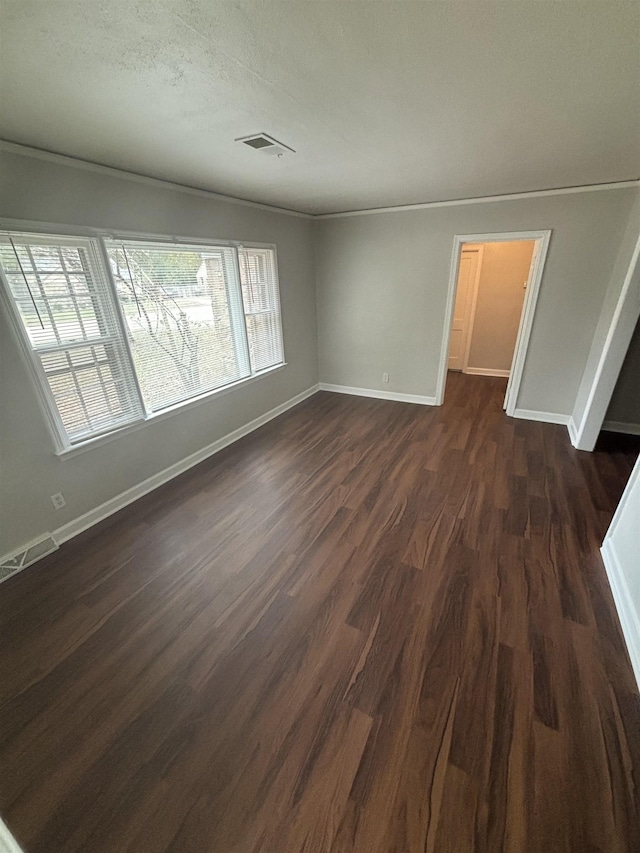 empty room featuring baseboards, visible vents, and dark wood-style flooring