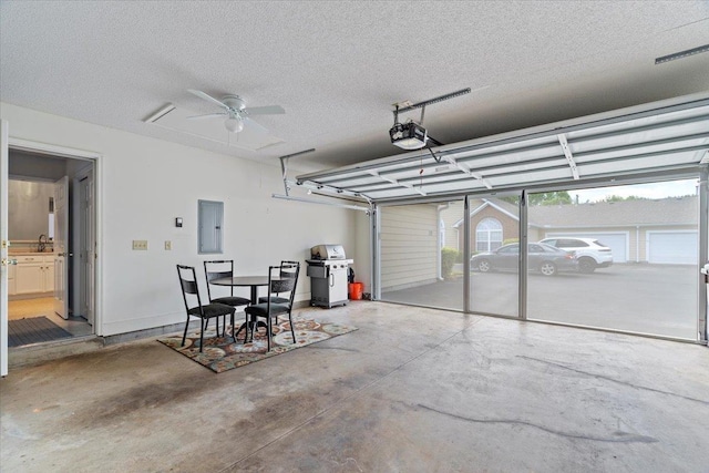 garage with a garage door opener, electric panel, ceiling fan, and a sink