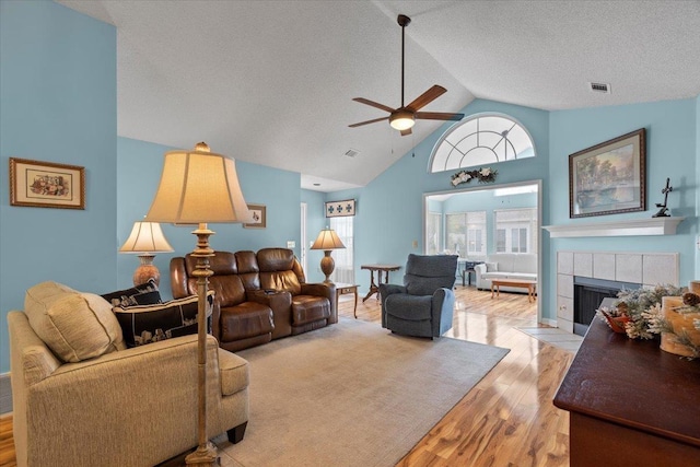 living area with a fireplace, wood finished floors, a textured ceiling, and a ceiling fan