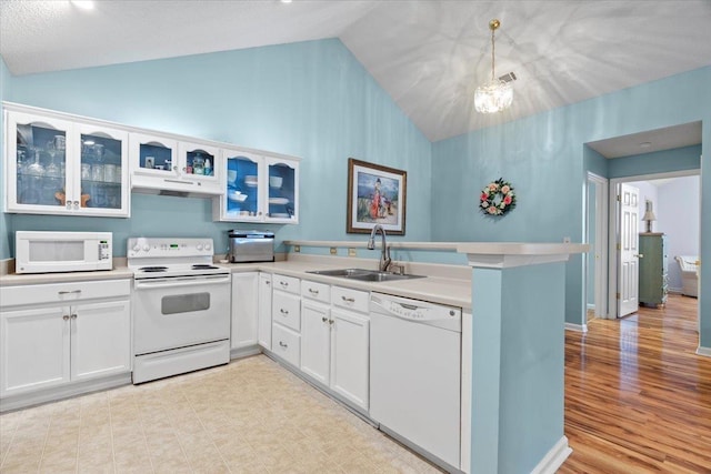 kitchen with a sink, white appliances, light countertops, lofted ceiling, and under cabinet range hood