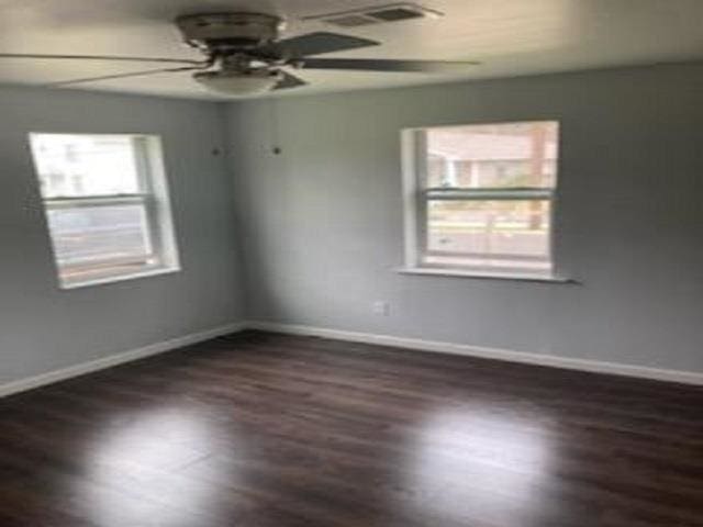 empty room featuring wood finished floors, a ceiling fan, and baseboards
