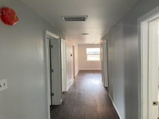 hall with baseboards, visible vents, and dark wood finished floors