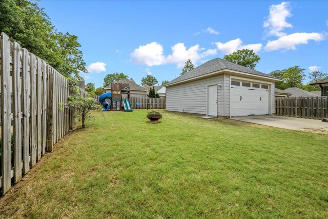 2363 Autumn Ave, Memphis, TN 38112 - view of yard featuring a fire pit, a detached garage, a fenced backyard, and a playground