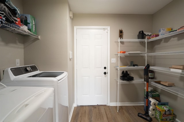 laundry room with washer and clothes dryer, wood finished floors, and laundry area