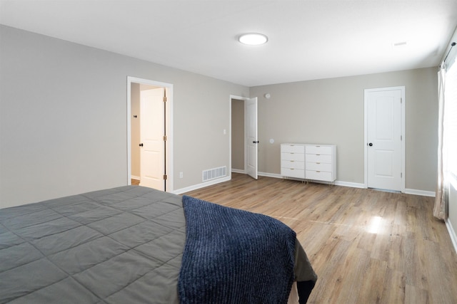 bedroom featuring baseboards, wood finished floors, and visible vents