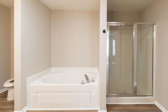 bathroom with a bath, a shower stall, toilet, and wood finished floors