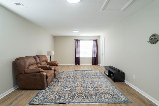 living room featuring light wood-type flooring, visible vents, and baseboards