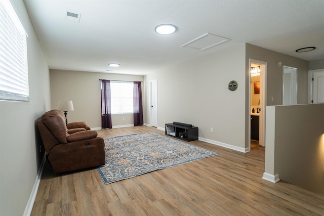 living room with attic access, baseboards, wood finished floors, and visible vents