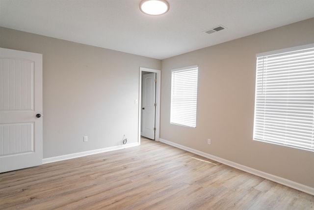 spare room with baseboards, visible vents, and light wood-style floors