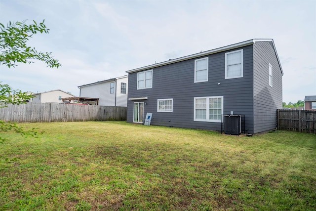 rear view of house with a fenced backyard, a yard, and central air condition unit