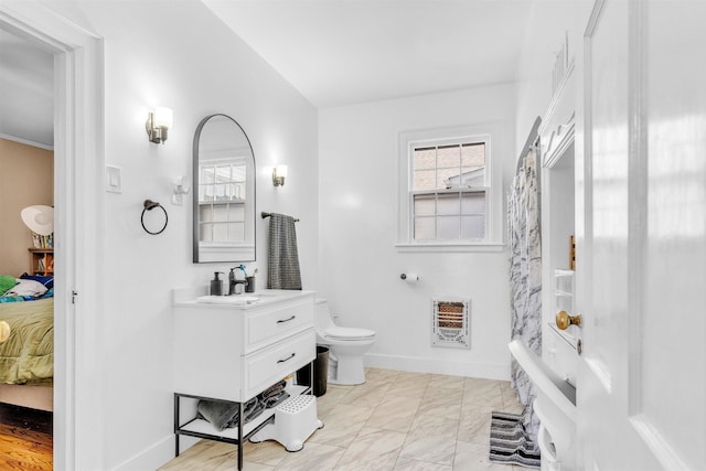 ensuite bathroom featuring a wealth of natural light, heating unit, connected bathroom, and toilet