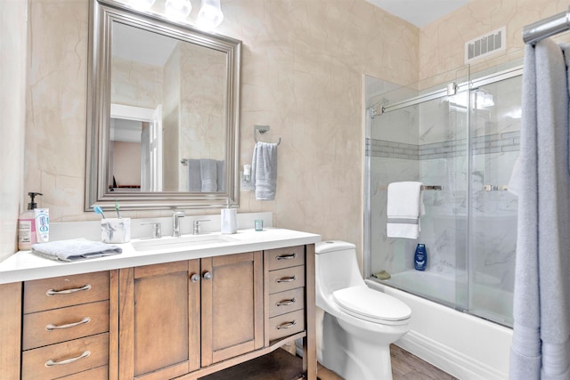 full bathroom with wood finished floors, visible vents, toilet, vanity, and bath / shower combo with glass door