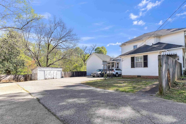 view of side of home with an outdoor structure, a shed, crawl space, and fence