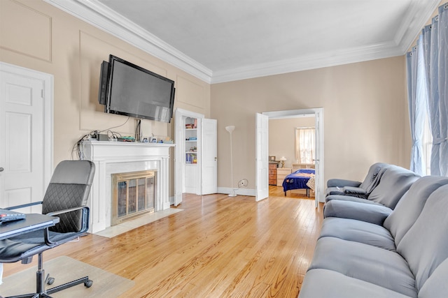 living room with a high end fireplace, light wood-type flooring, crown molding, and baseboards