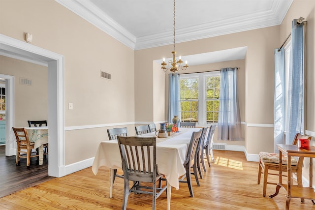 dining room with light wood-style floors, visible vents, and crown molding