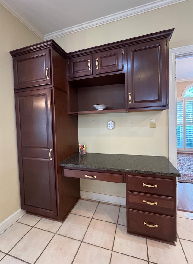 interior space with built in study area, ornamental molding, and dark brown cabinets
