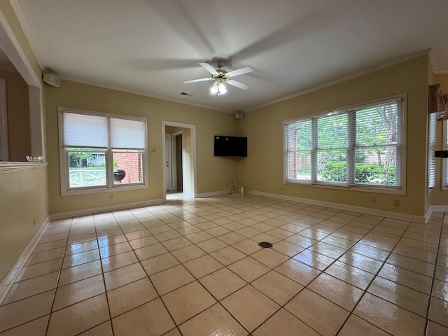 empty room with ceiling fan, baseboards, crown molding, and light tile patterned floors