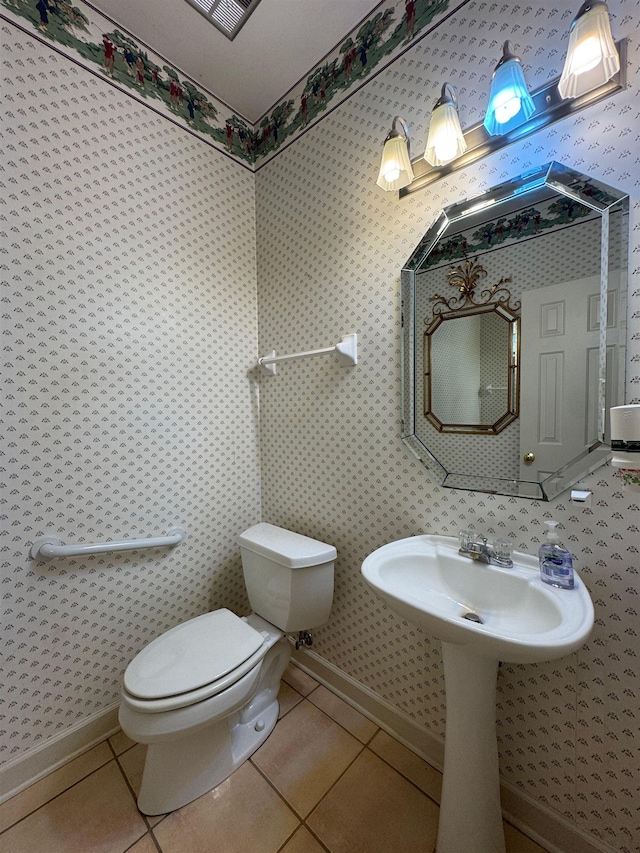 half bathroom featuring tile patterned flooring, wallpapered walls, toilet, and baseboards