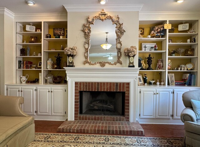 sitting room with a brick fireplace, dark wood-type flooring, and ornamental molding