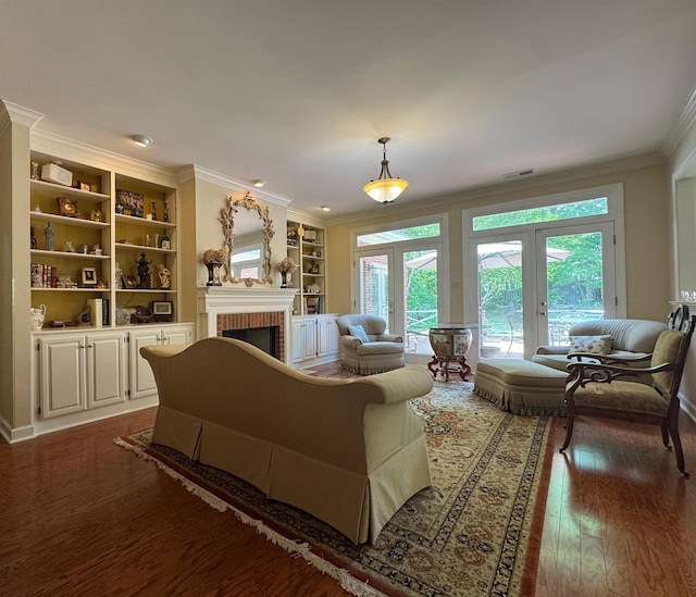 living room featuring a wealth of natural light, crown molding, a brick fireplace, and wood finished floors