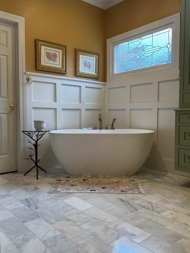 bathroom with wainscoting, a decorative wall, and a freestanding tub