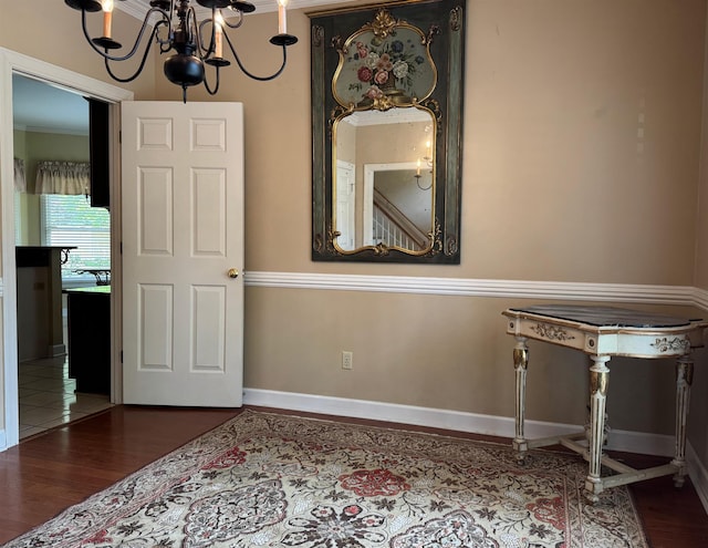 interior space with wood finished floors, crown molding, baseboards, and a notable chandelier