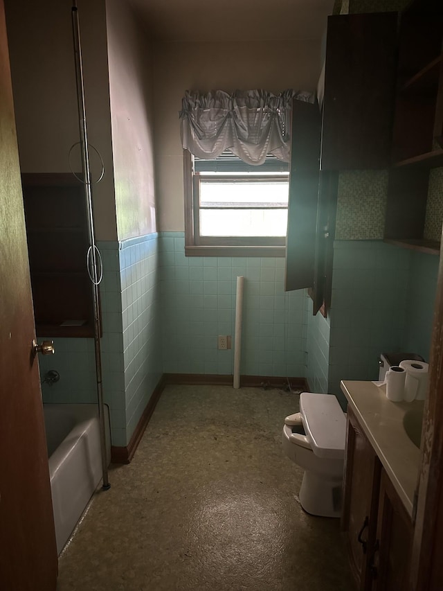 bathroom with a wainscoted wall, toilet, vanity, tile walls, and shower / bathing tub combination