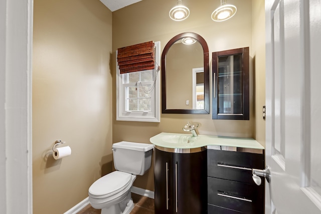 bathroom with toilet, vanity, and baseboards