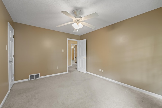 spare room with a ceiling fan, a textured ceiling, carpet, baseboards, and visible vents
