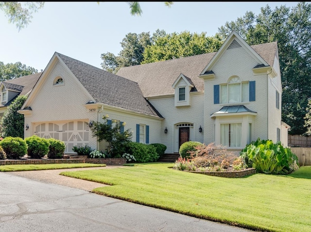 view of front of property with brick siding, a shingled roof, and a front yard