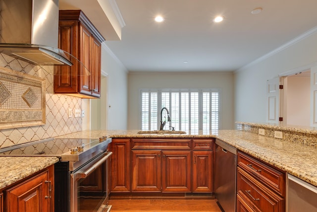 kitchen with ornamental molding, a sink, light stone countertops, wall chimney exhaust hood, and appliances with stainless steel finishes