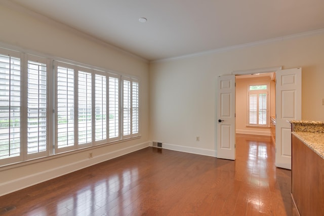 unfurnished room featuring wood-type flooring, crown molding, visible vents, and plenty of natural light