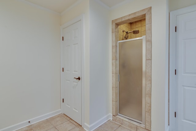 bathroom with crown molding, a shower stall, tile patterned flooring, and baseboards