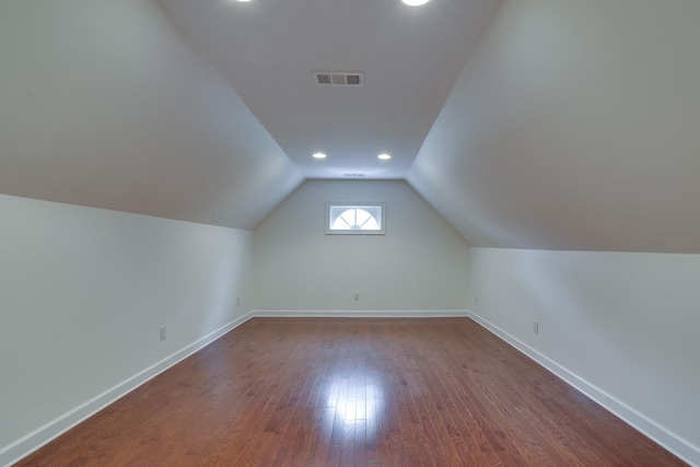 additional living space featuring visible vents, baseboards, lofted ceiling, dark wood-style floors, and recessed lighting